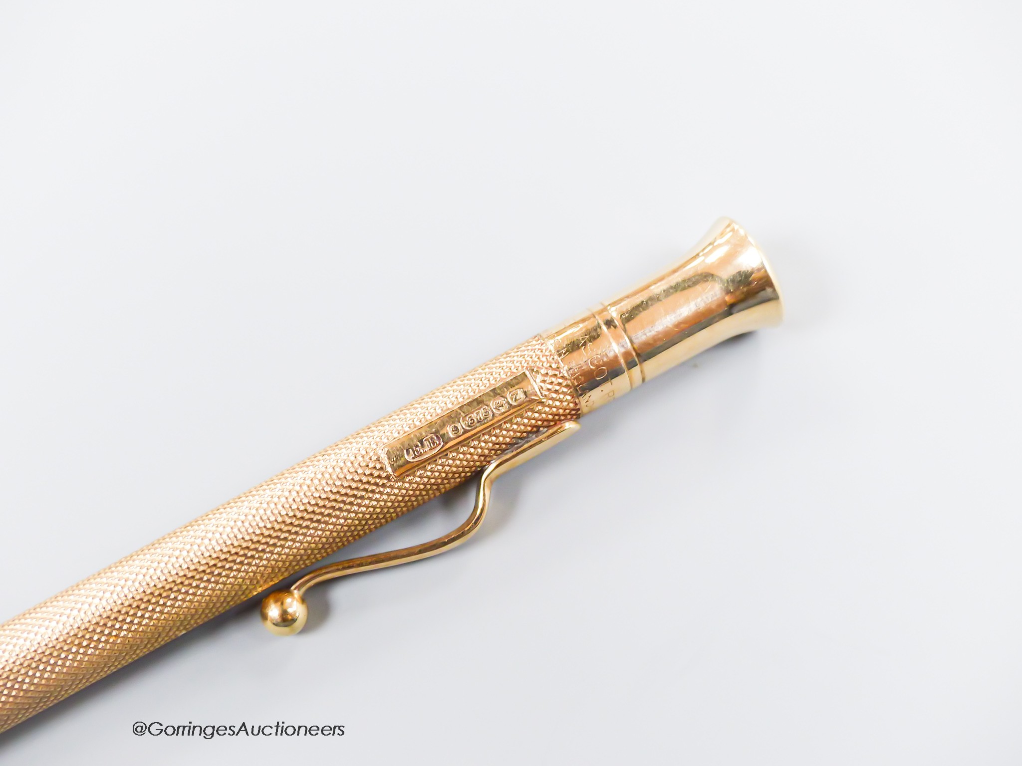 A late 1940's engine turned 9ct gold cased pencil, with engraved initials, 12.1cm.